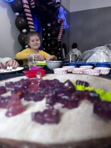 a girl sitting at a table with mydełka glicerynowe